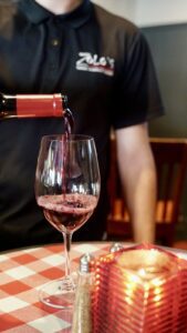 Person pouring a glass of wine at Zolo’s Italian Restaurant in downtown Franklin, TN.