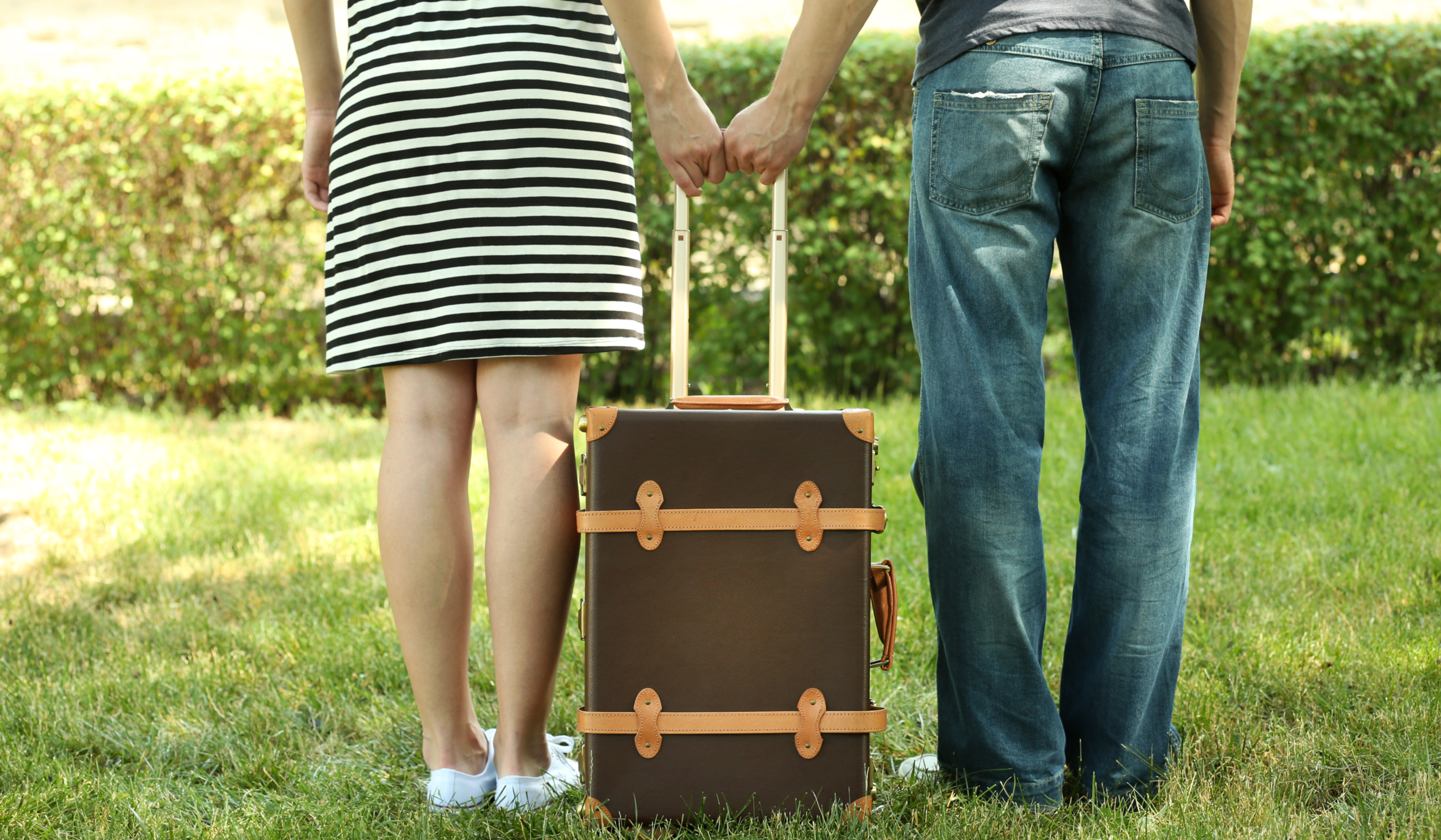 couple with suitcase in the grass