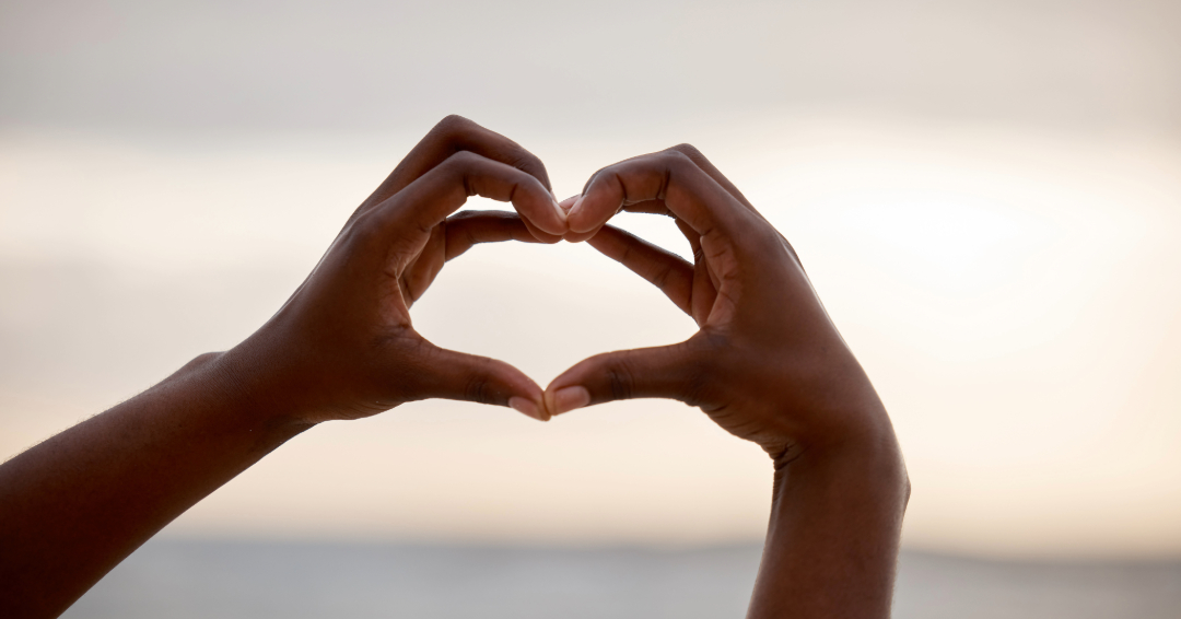 A woman makes a heart shape with her hands.