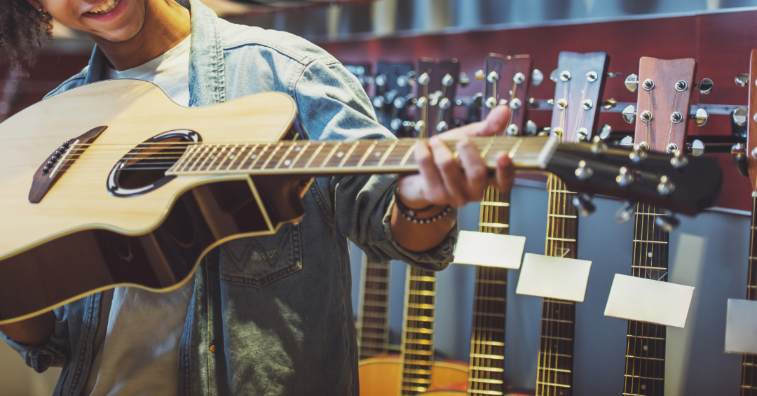 A man holding an acoustic guitar at a music store.
