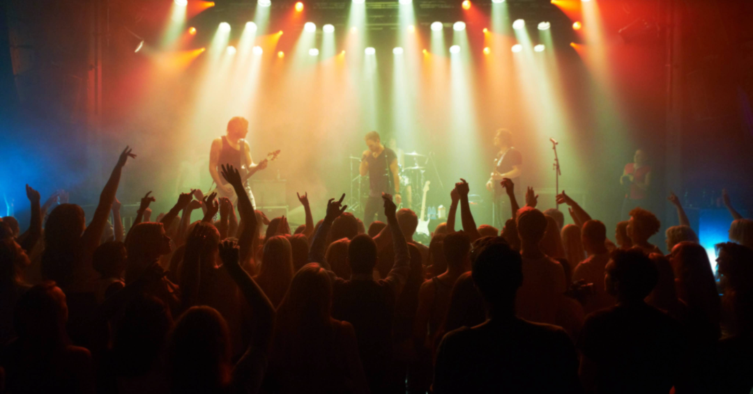 This is an image of a Franklin, Tennessee concert with colorful lights and silhouettes of a lively crowd cheering on a band.
