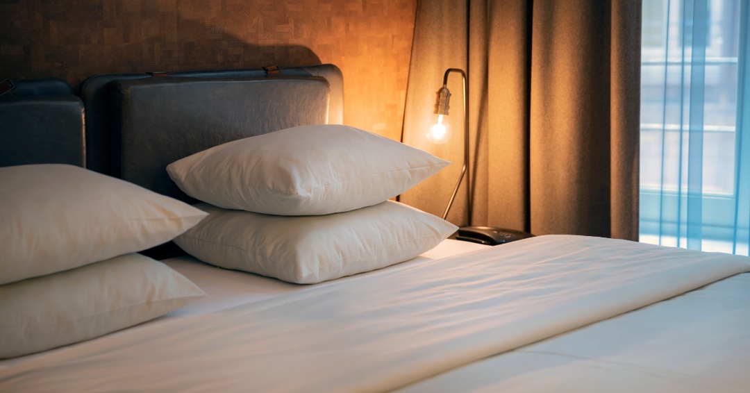 Hotel ideas for a Staycation in Franklin and Brentwood, TN, a hotel room photo of the head of a made bed at a hotel, with plush pillows and soft lamplight.