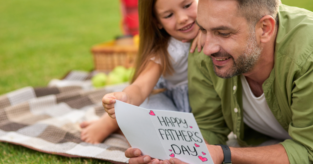 Dad and daughter with Father's Day card on the grass