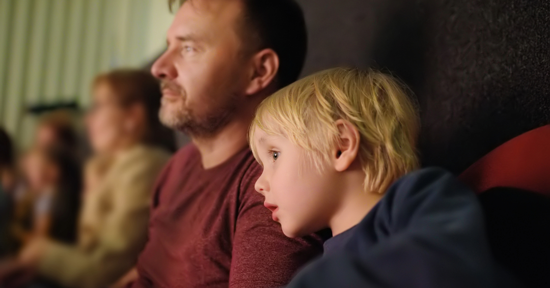 Father and son watching a movie in the theater for Father's Day