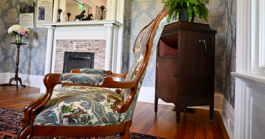 Hayes House Museum and Event Venue in Franklin, TN., antique chair in the sitting room with other antiques and a fireplace.