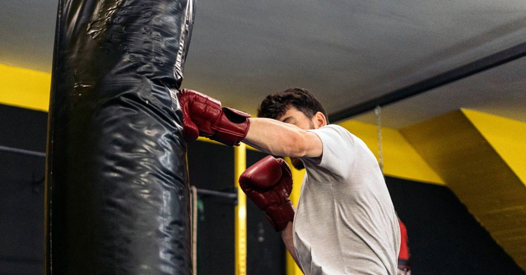 A man boxes a punching bag during a boxing workout. 