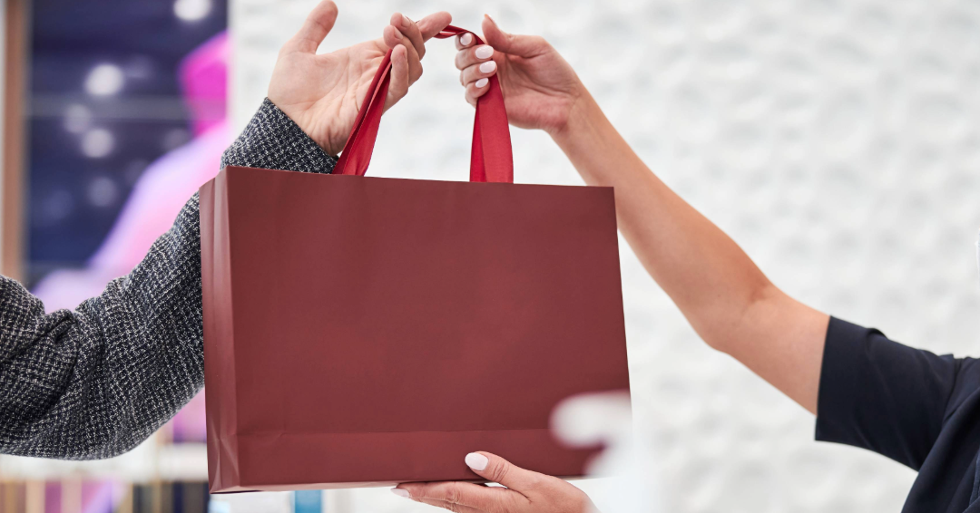 Discount shopping in Williamson County, Tennessee: A salesperson hands someone their purchase in a specialty bag.