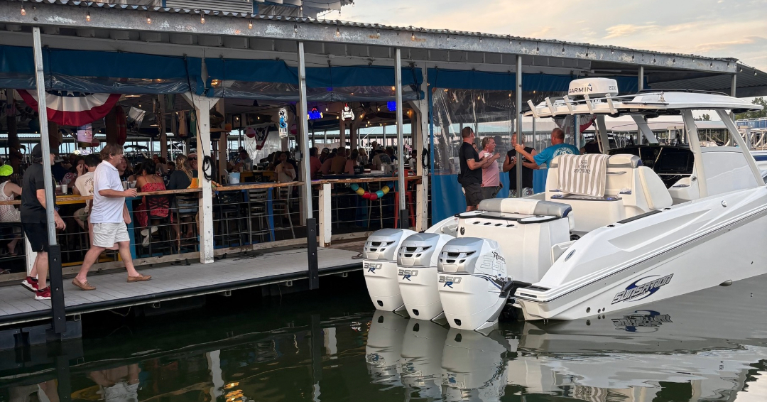Waterside dining in Nashville with guests at Scoreboard Bar and Grille gathered at a dockside restaurant beside a speedboat at Four Corners Marina.