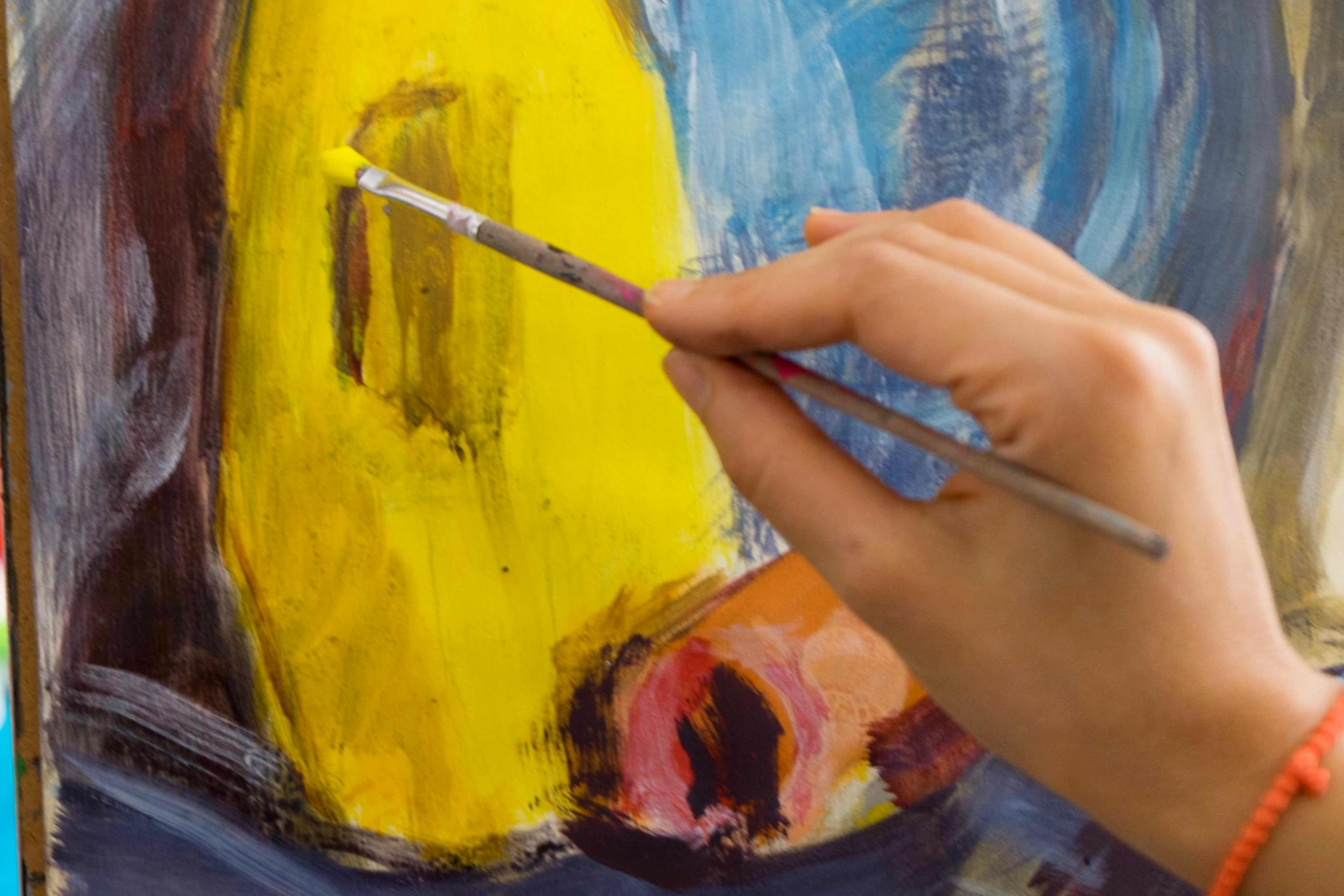 A woman paints yellow onto a canvas, showcasing the vibrant art scene in Williamson County, Tennessee. 