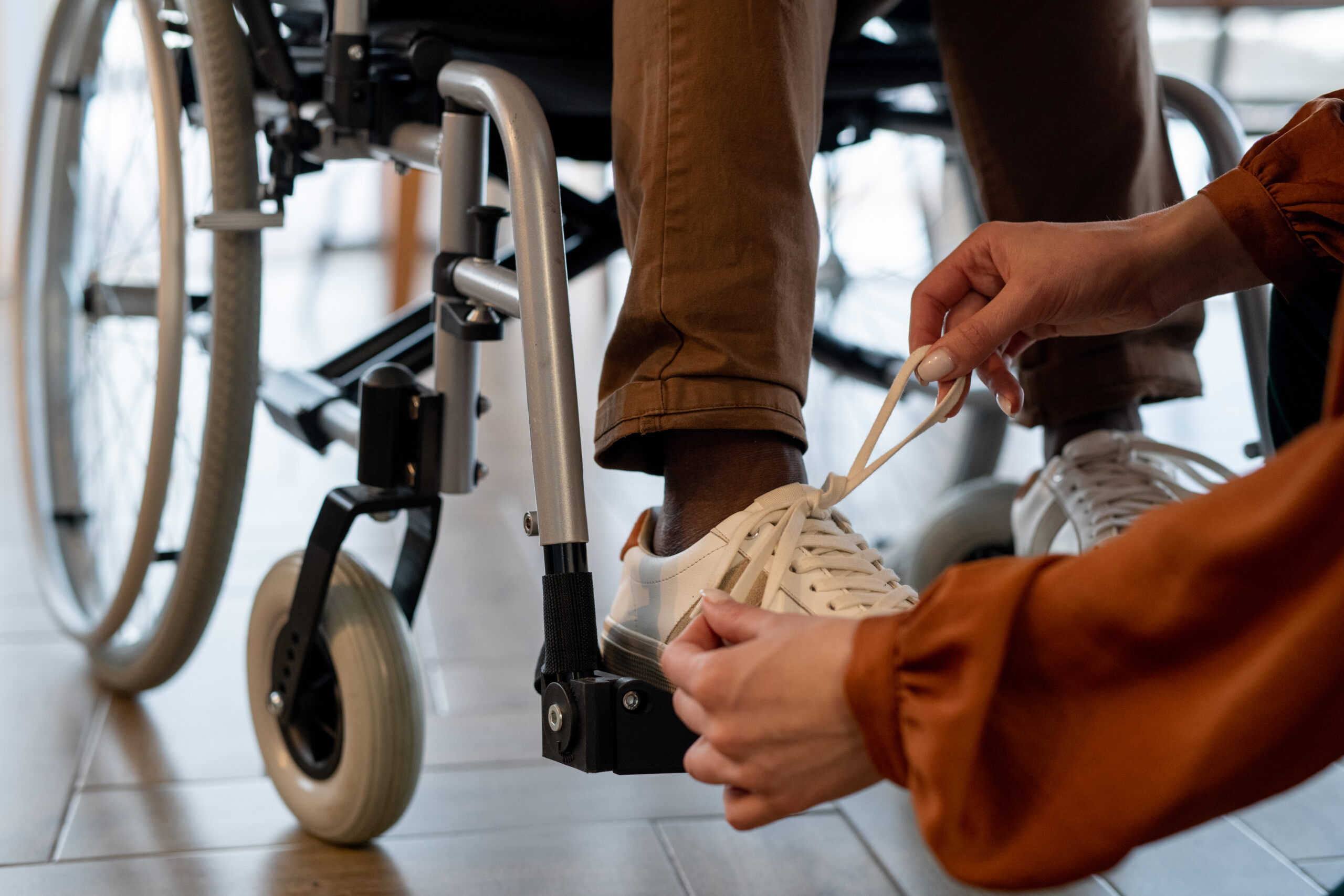 A woman ties the shoes of a man in a wheelchair. There are resources for those with disabilities in Williamson County, Tennessee. 