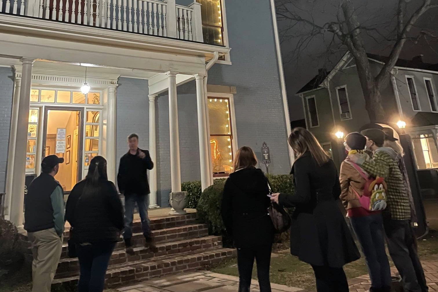 A guide leads a Franklin Ghost Tour group outside a historic home in downtown Franklin, Tennessee, sharing stories of the city’s haunted past under the evening lights.