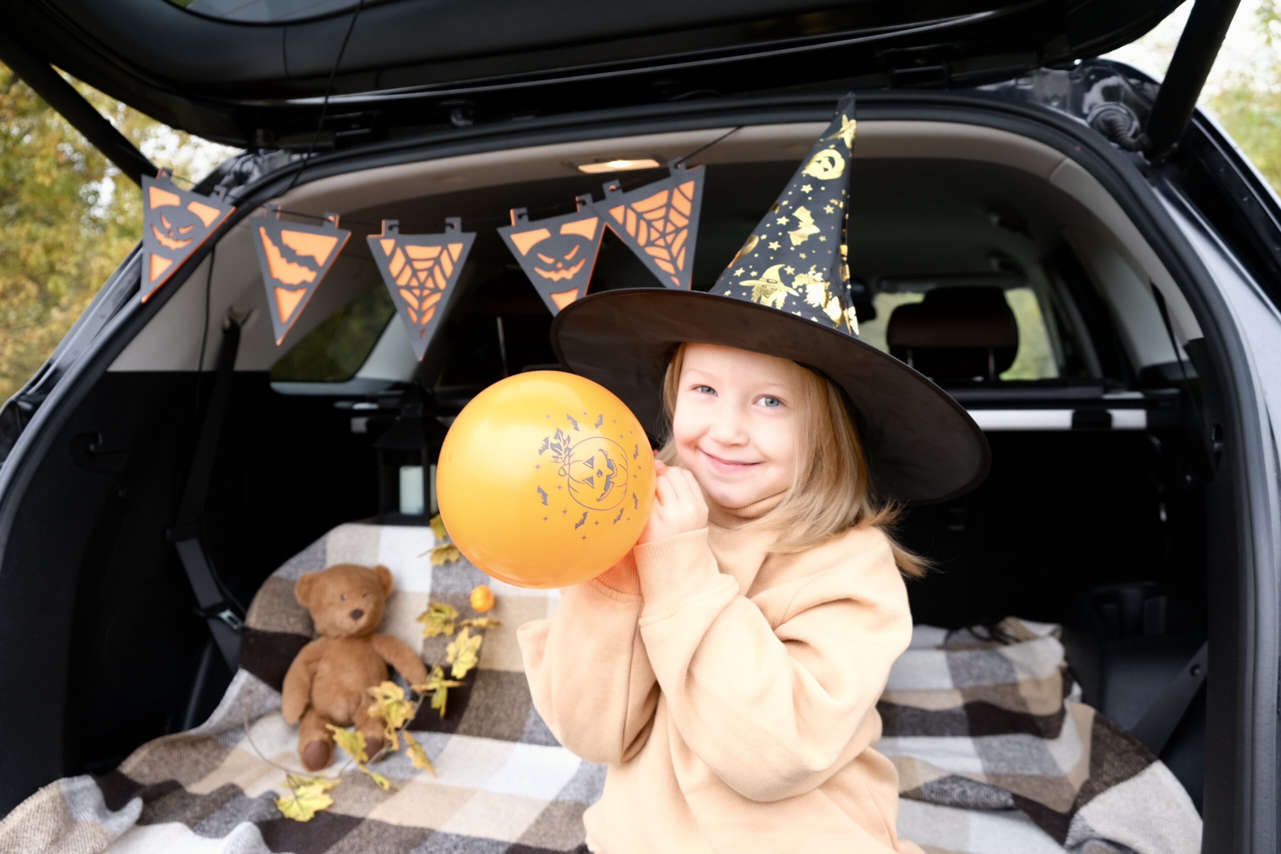 Trunk or Treat in Franklin, TN., a trunk with Halloween decor, and a child wearing a witches hat.